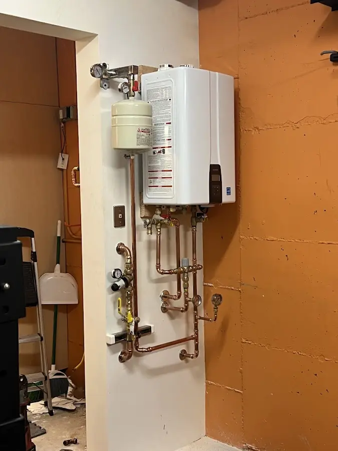 Plumbing technician inspecting water heater connections in Inkster